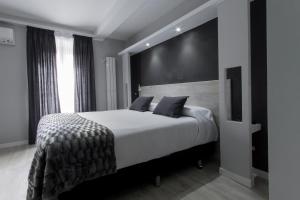 sypialnia z dużym białym łóżkiem z czarną ścianą w obiekcie Hostal Overnight Madrid w Madrycie