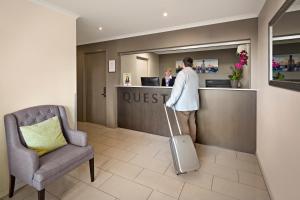 a man standing at a counter in a hotel with a suitcase at Quest Chermside in Brisbane +23 photos