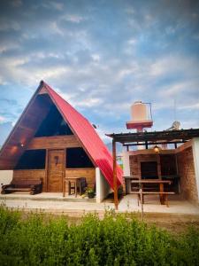 a house with a red roof with a table and a bench at La Encantad Cabañas - Amanecer in Cajamarca