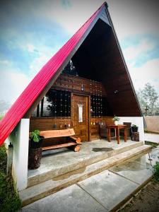 a house with a red roof with a bench and a table at La Encantad Cabañas - Amanecer in Cajamarca +1 photo