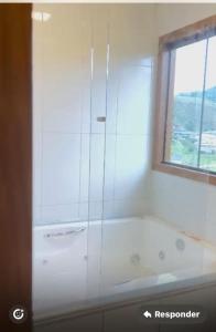 a white bath tub in a bathroom with a window at Chalés nas Montanhas in Domingos Martins +16 photos