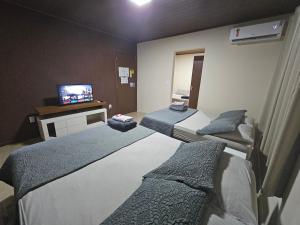a hotel room with two beds and a television at Hospedagem Costa BNU - PLUS in Blumenau