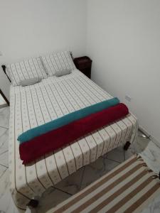 a white bed with a colorful blanket on it at Suíte Privativa in Paraty