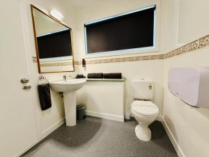 a white bathroom with a toilet and a sink at Colonial City Motel in Hamilton +9 photos