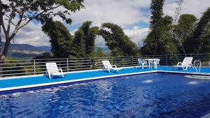 a swimming pool with two chairs and a table at Casa Campestre A5 in El Chocho