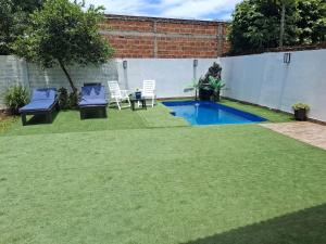a backyard with a small swimming pool and two chairs at Hospedaje Rural León in Encarnación