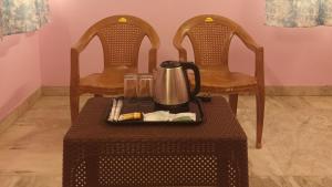 a tray with a tea kettle on a table with two chairs at La Vonto - Madurai Railway Junction in Madurai +12 photos