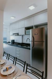 a kitchen with a refrigerator and a table with chairs at Apto moderno c/ Vista Incrível para o Mar in Itaparica