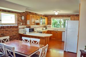 a kitchen with a table and a white refrigerator at Birchgrove Terrace 1 - Bring your own linen in South West Rocks