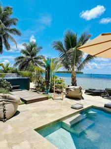 a swimming pool with an umbrella and the ocean at Pension Irivai appartement "Uparu" 1 chambre bord de mer in Uturoa