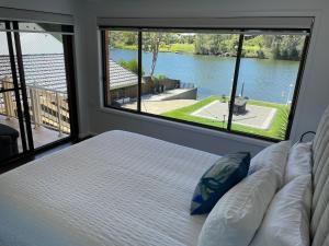 a bedroom with a bed and a large window at Waterfront Paradise with Jetty, BBQ, Pool table, & more in Dora Creek