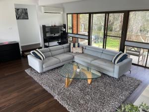 a living room with a couch and a glass table at Waterfront Paradise with Jetty, BBQ, Pool table, & more in Dora Creek