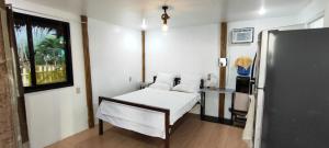 a small room with a bed and a refrigerator at John and Novy Camotes Beach Bungalows in San Francisco