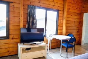 a living room with a tv and a table and a chair at Bounty Motel in Paihia