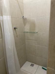 y baño con ducha y estante de cristal. en Kitnets Prático Aconchego, en Petrolina