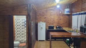 a kitchen with a refrigerator and a table in it at Cabaña La 40 "Relax y descanso en zona de chacras" in Buta Ranquil