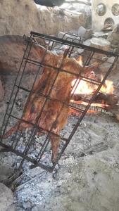 a piece of meat is cooking over a fire at Cabaña La 40 "Relax y descanso en zona de chacras" in Buta Ranquil
