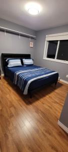 a bedroom with a bed with a blue comforter and a window at Rustyc Charm Meets Modern Comfy in Dieppe