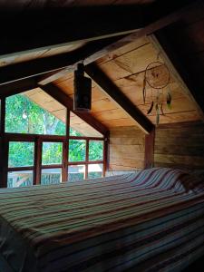 a bedroom with a bed in a room with windows at cabaña Lechuza café in Juayúa