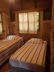 two beds in a room with two windows at cabaña Lechuza café in Juayúa +4 photos