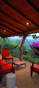 a porch with a hammock and chairs and flowers at cabaña Lechuza café in Juayúa
