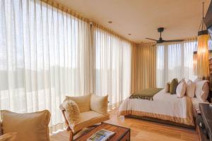 a bedroom with a bed and a chair at Trobbu Boutique Collection Riviera Maya - All inclusive in Tulum