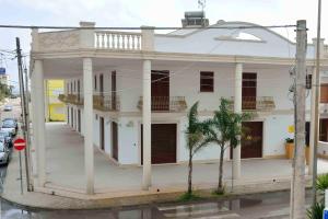 a white house with a palm tree in front of it at Spazi Preziosi in Torre San Giovanni Ugento