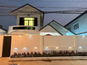 una cerca blanca frente a una casa con luces en G Cozy Pool Villa, en Pattaya South