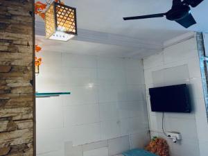 Zimmer mit einem TV und einer gefliesten Wand in der Unterkunft Den near the sea in Mumbai