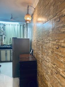 Zimmer mit Ziegelwand und Holztisch in der Unterkunft Den near the sea in Mumbai