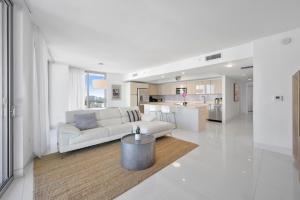 Una sala de estar blanca con un sofá y una mesa. en Luxury 3BR With Stunning Views on High Floor, en Hallandale Beach