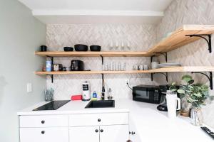 a kitchen with white counters and wooden shelves at BRANDNEW 2023 LAKEFRONT APT in Kissimmee