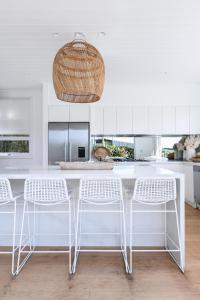 a kitchen with a white counter and white chairs at Warriewood beach house in Mona Vale