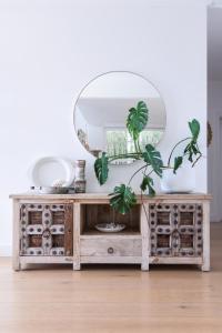 a mirror on top of a wooden dresser with plants at Warriewood beach house in Mona Vale +27 photos