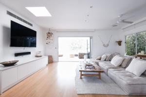 a white living room with a couch and a table at Warriewood beach house in Mona Vale