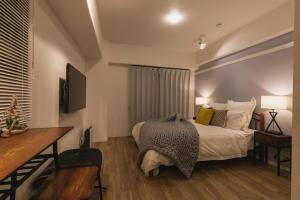 a bedroom with a bed and a desk and a television at 5D Guest House INFINITY in Naha