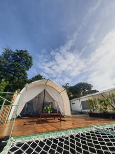 a white tent with a wooden table on a deck at Tepas Glamping in Ciburial