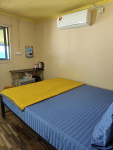 a bedroom with a bed with a yellow blanket at Permata Beach Chalet in Kampong Juara