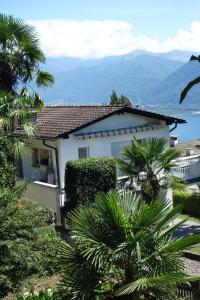 une maison blanche avec des palmiers et des montagnes en arrière-plan dans l'établissement Casa Angela, à Locarno
