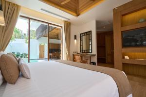 a bedroom with a large bed with a large window at Malisa Villa Suites - SHA Extra Plus in Kata Beach +70 photos