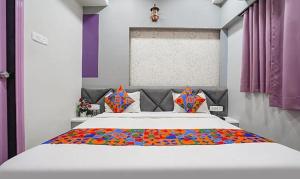 a bedroom with a large white bed with colorful pillows at FabHotel Imperial Suites in Nagpur