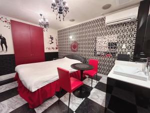 a bedroom with a bed and a table and red chairs at ホテルフローレスツーadultonly in Tsubame