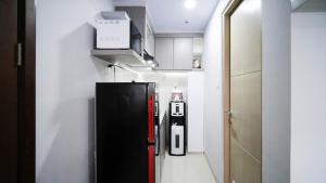 cocina con nevera negra en una habitación en Nice and Comfy Studio at Grand Dharmahusada Lagoon Apartment By Travelio, en Surabaya