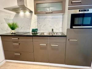 a kitchen with a sink and a microwave at Luxury Suites Castel by Rikas Hotels in Antwerp
