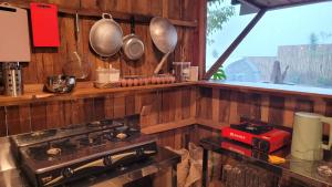 a kitchen with wooden walls and a stove and a window at Tepas Glamping in Ciburial