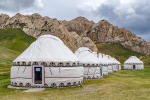 a row of white domes in front of a mountain at Tash-Rabat Ethno complex in At-Bashy