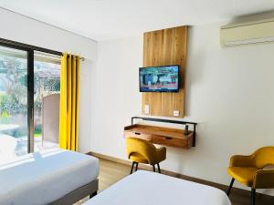 a bedroom with a bed and a desk and a tv at Hôtel Le Colombier in Moustiers-Sainte-Marie