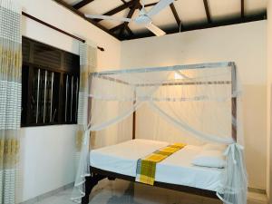 a bed with a mosquito net in a room at Villa33 in Weligama