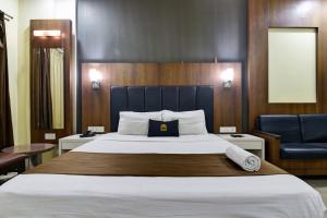 a bedroom with a large bed and a chair at Hotel Devanshi & Banquets by Classy Stay in Navi Mumbai +31 photos