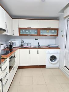 a kitchen with white cabinets and a washing machine at Red Wine Haro, piscina y parking in Haro